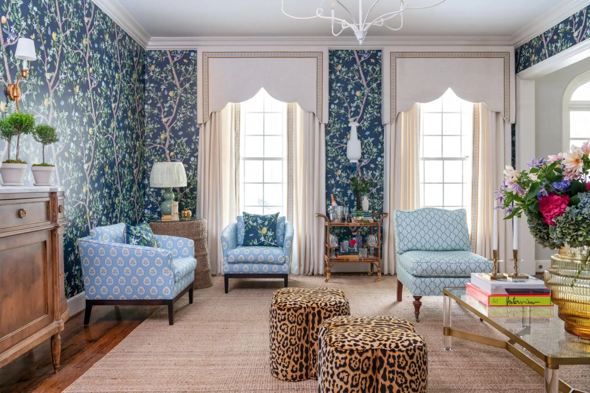 a formal living room with leopard stools and navy blue floral wallpaper