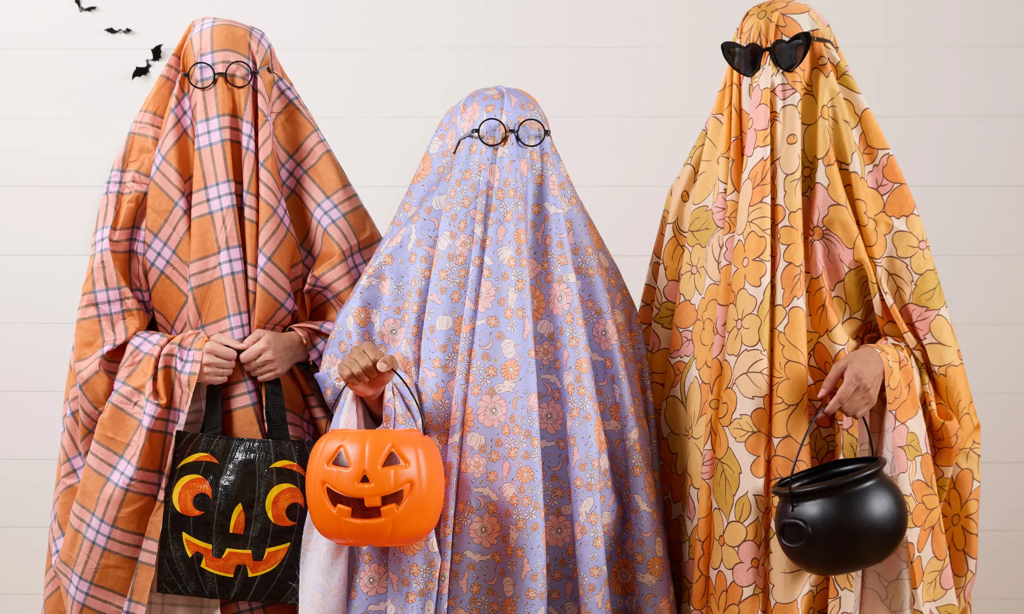 Three people in retro inspired patterned sheet ghost costumes