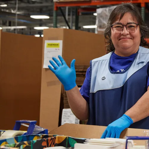 Person waving while working at manufacturing facility