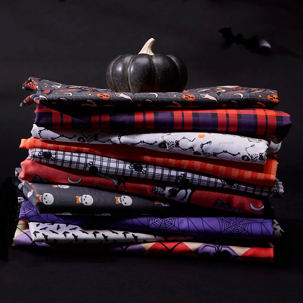 A halloween inspired fabric stack with bats and purple thread in the background.