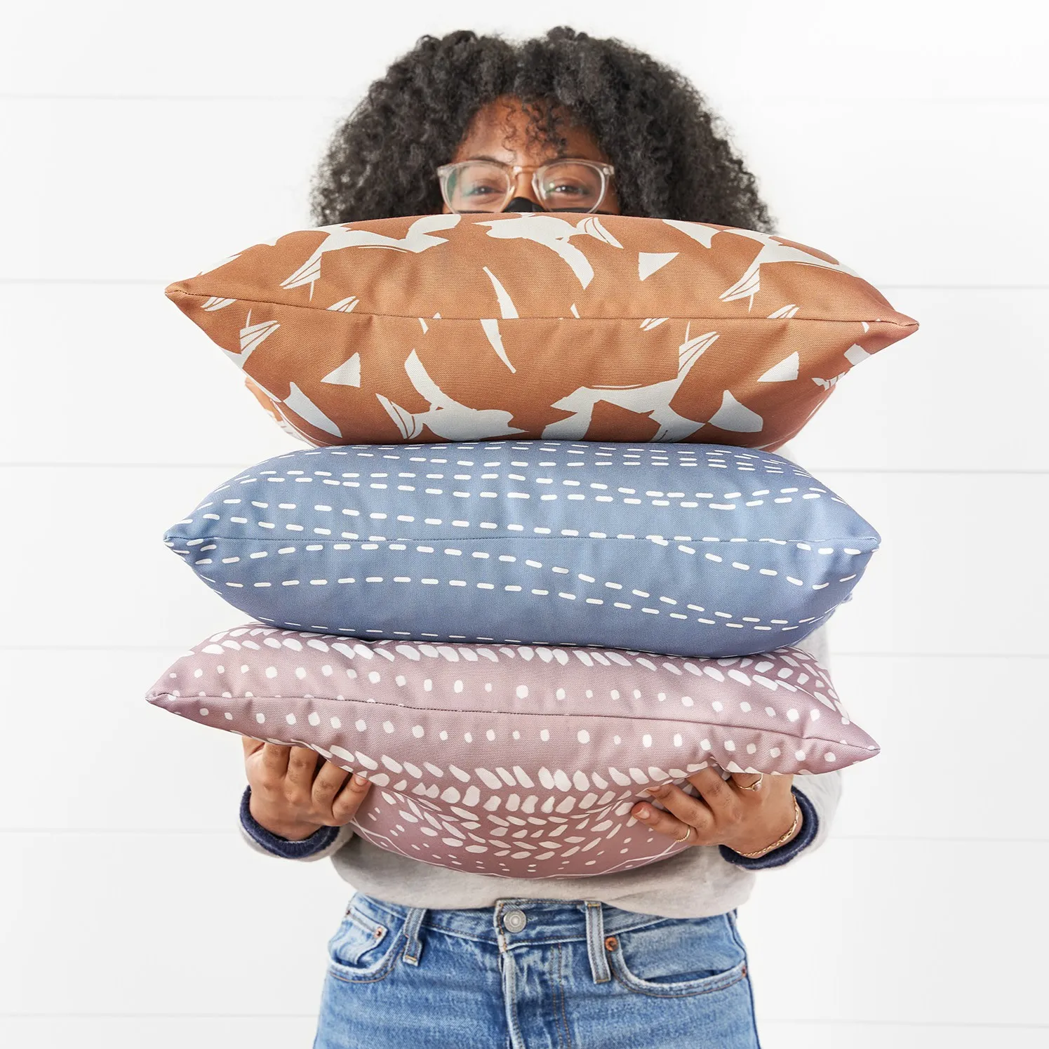 Person holding three throw pillows